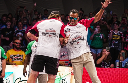two guys cheering for the win they had in corn hole