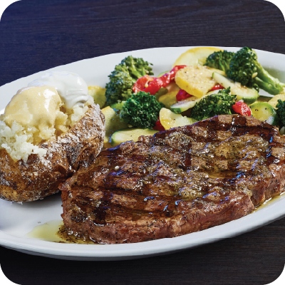 ribeye steak with a baked potato and veggies